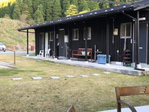 a black building with chairs in the grass at Resort Oguni in Oguni