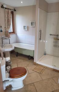 un bagno con un water, una vasca e un lavandino di The Round House at Boningale Manor a Wolverhampton Altre 6 foto