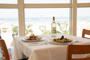stół z dwoma talerzami jedzenia i butelką wina w obiekcie Blue Paradise Hotel w San Mauro a Mare