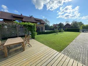 a wooden deck with a bench and a yard at Karkle SummerHOUSE, sea view villa in Karklė