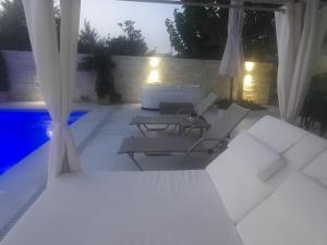 een patio met stoelen en 's nachts een zwembad bij Amare suite in Perivólia