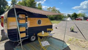 a black and yellow trailer with a table in it at Cabrio-Wohnwagen in Brandenburg an der Havel