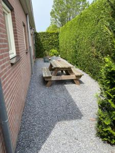 a wooden picnic table sitting next to a brick wall at La-Perchade in Huissen +6 photos