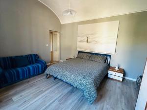 a bedroom with a bed and a blue couch at Palazzo Motta - MonferratoHome in Vignale