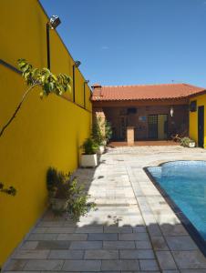 una casa amarilla con piscina frente a ella en Pousada Acolhedora, en Ribeirão Preto