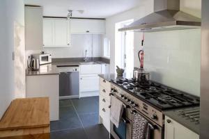 a kitchen with white cabinets and a stove top oven at Charlestown cottage, Woodburner, Gardens & Parking in Charlestown
