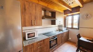 特里斯格蘭達斯的住宿－La Casina de Marina de Tresgrandas，一间带木制橱柜和微波炉的厨房