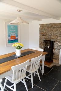 a dining room table with white chairs and a stone fireplace at Charlestown cottage, Woodburner, Gardens & Parking in Charlestown