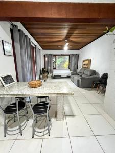 a kitchen and living room with a table and chairs at Casa Maresias Canto do mar - 50m da praia in Maresias