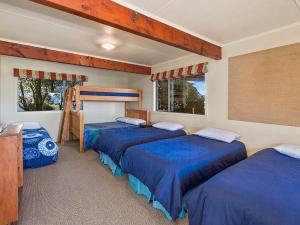 Waitahanui的住宿－Absolute Waterfront with WiFi - Five Mile Bay Home，一间卧室配有三张床,铺有蓝色的床单。