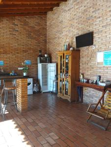 uma cozinha com um frigorífico e uma televisão numa parede de tijolos em Pousada Acolhedora em Ribeirão Preto
