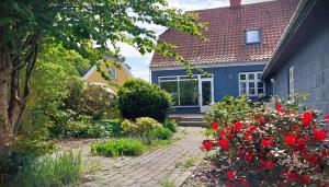 a blue house with red flowers in a garden at Room in Ubby (Near Kalundborg) in Kalundborg