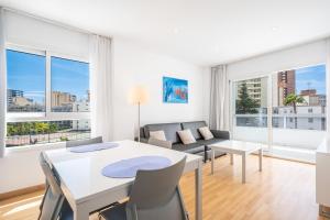 a living room with a table and chairs and a couch at Apartamentos Les Dunes Centro Levante Beach in Benidorm
