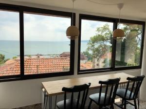 a dining room with a table and four chairs and windows at Studio with a sea view in Balchik
