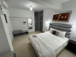 1 dormitorio con 1 cama blanca grande y espejo en Miskisol, en Piura