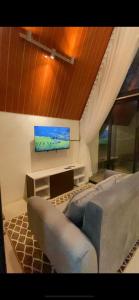 ein Wohnzimmer mit einem Sofa und einem Flachbild-TV in der Unterkunft AGRIYA LUBIS CABIN in Diyeng