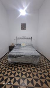 a bedroom with a bed with a black and white floor at Alojamiento Orellana in Orellana la Vieja