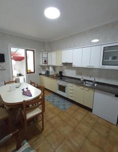 - une cuisine avec des placards blancs, une table et des chaises dans l'établissement Amodiño,casa alquiler vacacional, à Viveiro