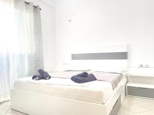 Un dormitorio blanco con una cama con toallas. en Ernest Apartments, en Sarandë