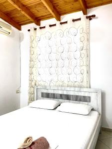 1 dormitorio con cama blanca y cabecero en Ernest Apartments, en Sarandë