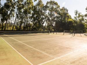un court de tennis avec un filet et des arbres en arrière-plan dans l'établissement Les Appartements aux Restanques du Golfe de St Tropez - maeva Home - Appartem 88, à Grimaud