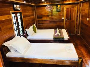 two beds in a room with wooden walls at Retro Kampot Guesthouse in Kampot