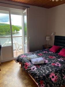 a bedroom with a bed and a balcony with a view at LES TERRASSES DU LAC in Chaumard