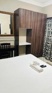 sypialnia z białym łóżkiem i drewnianą szafką w obiekcie Sunrise Boutique Hotel w mieście Witbank