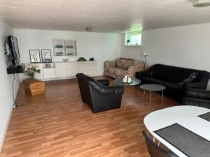 uma sala de estar com mobiliário de couro preto e pisos em madeira em Skovbrynet 2 Zimmer 4 em Lokken