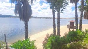 a bench on a beach next to a body of water at Alojamiento Orellana in Orellana la Vieja
