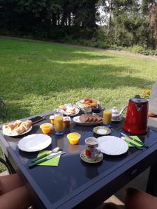 a picnic table with plates of food and orange juice at Chambre d'hôtes du schneeberg in Alteckendorf