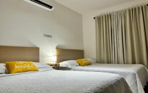 2 camas en una habitación de hotel con almohadas amarillas en EXCELENTE CASA RESIDENCIAL PRIVADO- ALBERCA-SEGURIDAD 24-7-ac, en Ciudad Valles