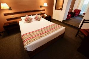 a hotel room with a large bed with two pillows at Hotel Raymi in Cusco