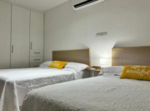 1 dormitorio con 2 camas con sábanas blancas y almohadas amarillas en EXCELENTE CASA RESIDENCIAL PRIVADO- ALBERCA-SEGURIDAD 24-7-ac, en Ciudad Valles