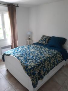een slaapkamer met een bed met een blauw dekbed bij Villa Maison Cévennes et Sud Ardèche in Bessèges