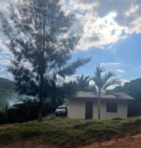 ein weißes Haus mit einem Auto neben einem Baum in der Unterkunft Casa de campo in Presidente Soares