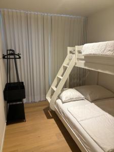een wit stapelbed in een kamer met een raam bij Vakantieappartement Oostende in Oostende