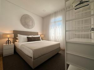 a white bedroom with a bed and a window at Achada Sol in Funchal