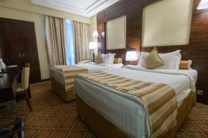 a hotel room with two beds and a desk at Ruve Al Madinah Hotel in Al Madinah
