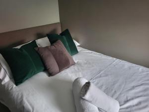 - un lit blanc avec des oreillers verts et bruns dans l'établissement Tren-D Luxe Studio Apartment Room 3 - Contractors, Relocators, Profesionals, NHS Staff Welcome, à Sunderland