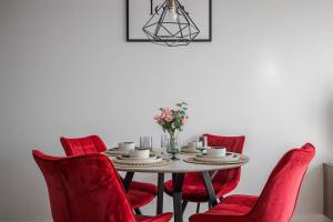 a dining room table with red chairs and a vase of flowers at Home sweet home, cozy apartments, free underground parking, long stays welcome in Vilnius