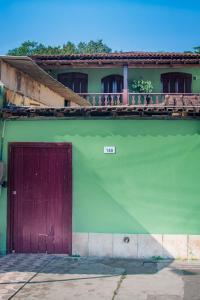 - un bâtiment vert avec une porte rouge et un balcon dans l'établissement Casa Surya Paraty, à Parati