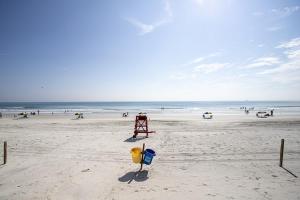 una spiaggia con stand del bagnino e persone sulla spiaggia di SeaBliss, oceanfront 1st floor cozy condo a Daytona Beach