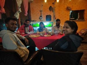 un grupo de personas sentadas alrededor de una mesa en Shiva Valley Riverside Home Stay en Jibhi