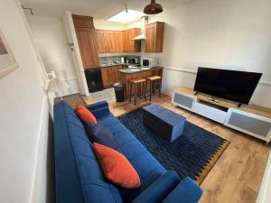a living room with a blue couch and a kitchen at Cute 1 bed flat in Southwold in Southwold