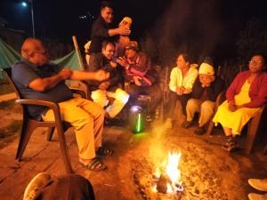 un grupo de personas sentadas alrededor de un fuego en Shiva Valley Riverside Home Stay en Jibhi