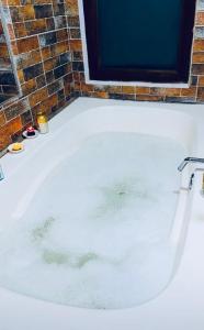 a bath tub filled with water next to a brick wall at MALOKAS AGUA VIDA & NATURALEZA in Villa de Leyva