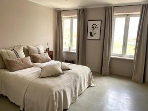 um quarto com uma grande cama branca e janelas em Casa Bianchetti em Costigliole dʼAsti