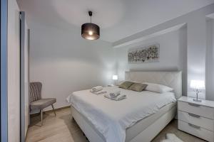a white bedroom with a bed and a chair at Apartment Luana with private pool in Poreč