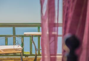 una mesa y una silla en un balcón con una cortina roja en Althea Archontika Tis Androu en Batsi